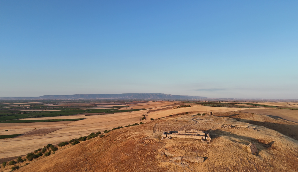 Veduta aerea al tramonto del sito archeologico di Castel Fiorentino a Torremaggiore, con i ruderi della domus federiciana illuminati dal sole.