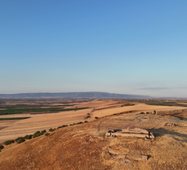 Veduta aerea al tramonto del sito archeologico di Castel Fiorentino a Torremaggiore, con i ruderi della domus federiciana illuminati dal sole.