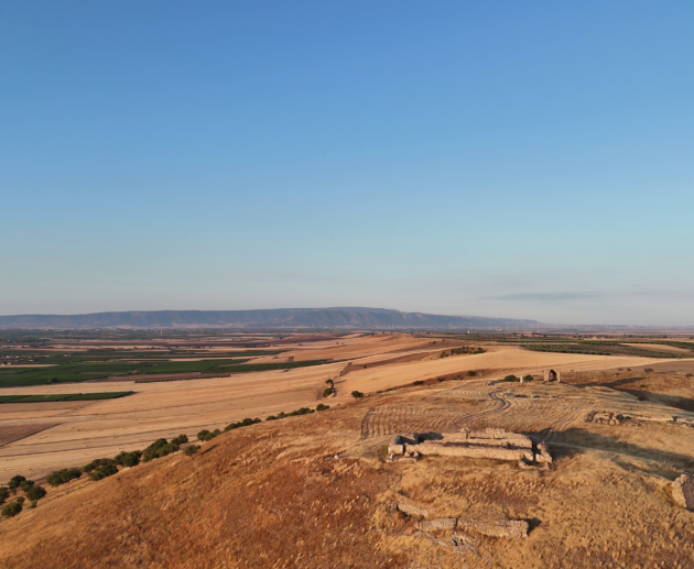 Veduta aerea al tramonto del sito archeologico di Castel Fiorentino a Torremaggiore, con i ruderi della domus federiciana illuminati dal sole.